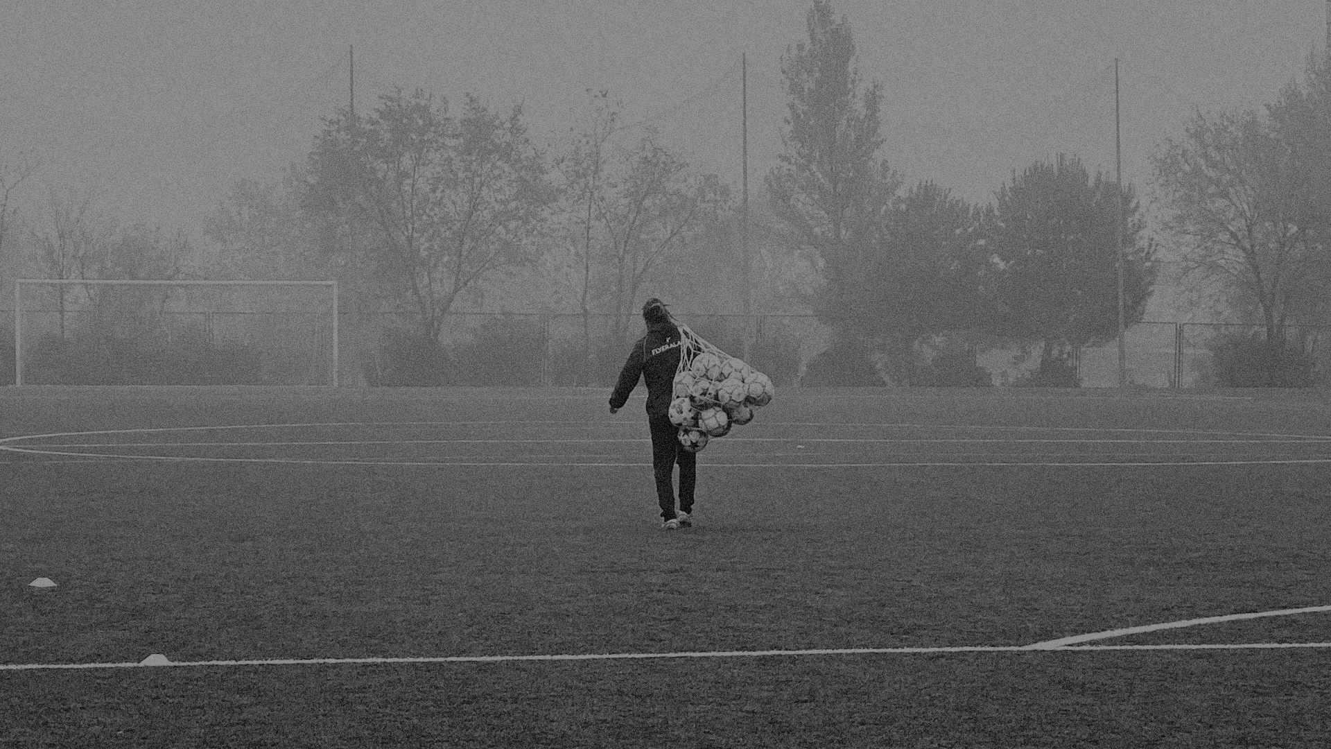 Soccer coach carrying a bag of soccer balls