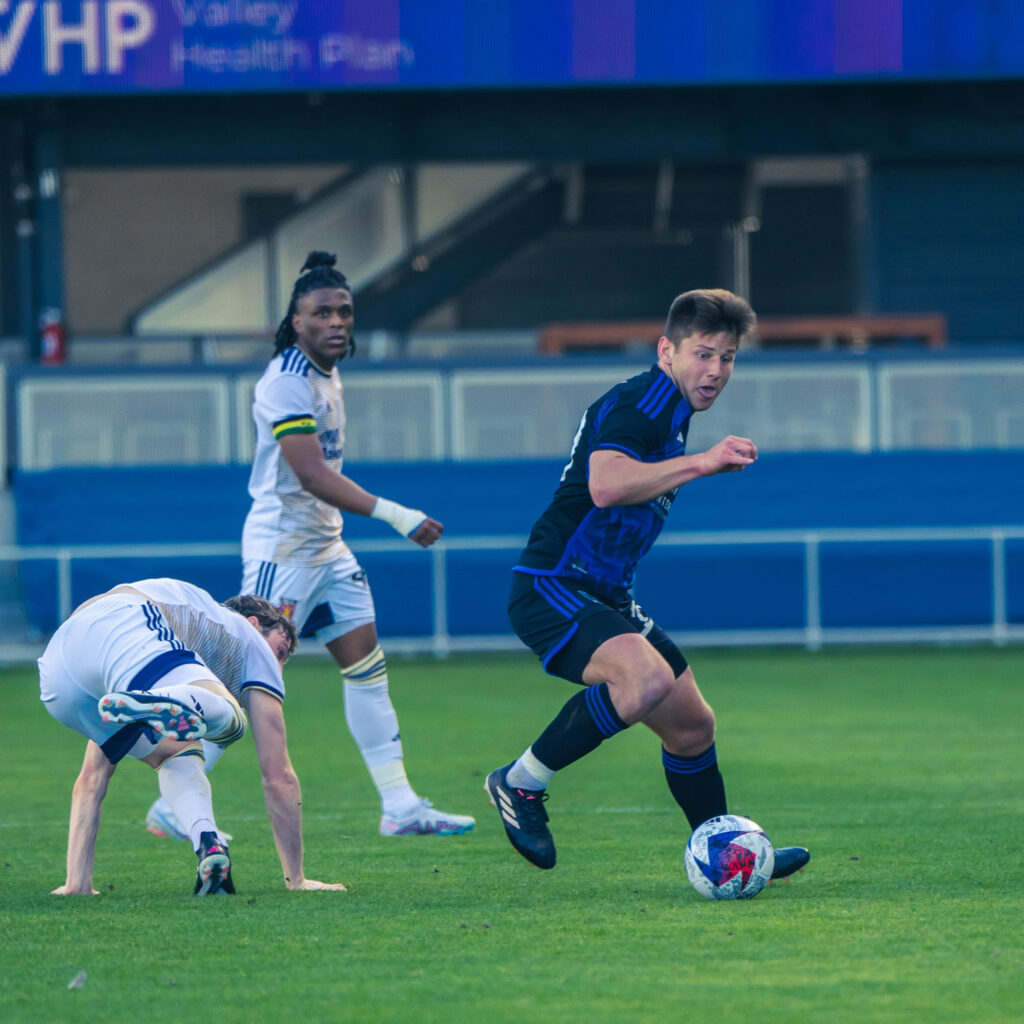 Cam Cilley on the pitch dribbling past a defender